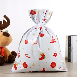 Détail du sac cadeau de Noël avec père Noël, flocons dorés et ruban de serrage blanc