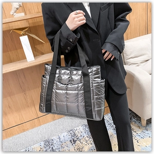 Close-up of quilted silver puffer tote bag featuring side pockets and a wide strap