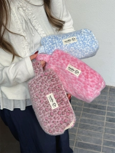Close-up of colorful leopard plush pouches held by a model showcasing soft texture