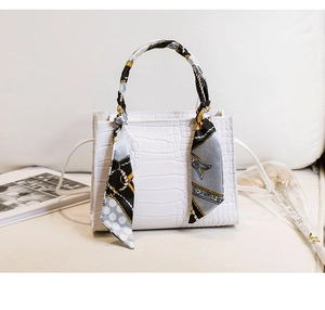 Détail d'un sac à main blanc motif crocodile avec foulard en soie sur la poignée et bandoulière