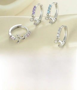 Detail view of bow earrings with zircon inlays in purple, blue, white, and pink