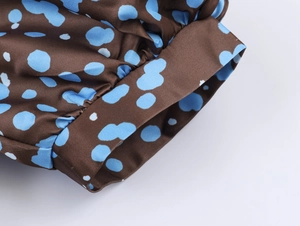 Detail view of elegant brown satin puff sleeves with blue polka dot pattern texture