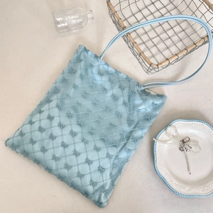 Détail du sac cabas matelassé bleu avec broderies de nœuds délicats et texture fine