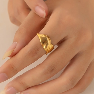 Detail of a minimalist gold wavy ring with a matte finish on a model's index finger