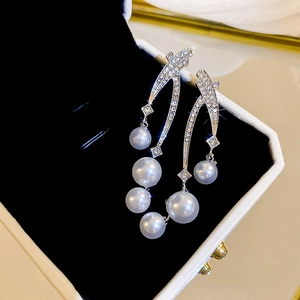 Détails de boucles d'oreilles argentées avec zircons et perles blanches dégradées