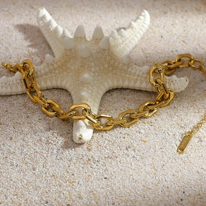 Detail of 18K gold plated stainless steel chunky chain bracelet on a starfish and sand