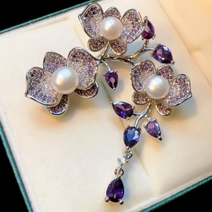 Luxury orchid brooch with purple cubic zirconia and white pearls in a cream jewelry box