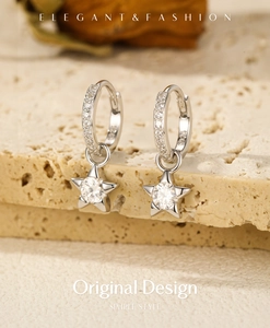 Close-up of S925 sterling silver star drop earrings with moissanite on stone surface