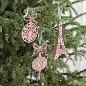 Pink and rose gold Christmas tree ornaments with snowflakes and Eiffel Tower on green branches