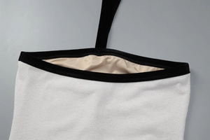 Détail de maille côtelée avec bordure en velours et licou sur une robe blanche