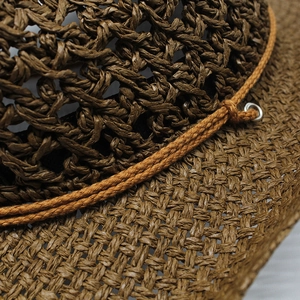 Detail shot showing the intricate hollow crochet weave and brown straw texture of the cowboy hat