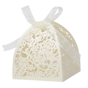 Detail of cream laser cut wedding candy box with floral patterns and a ribbon bow
