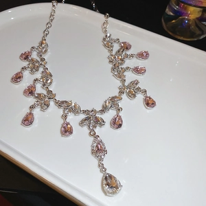 Macro detail of teardrop tassel necklace set with pink crystal and leaf design