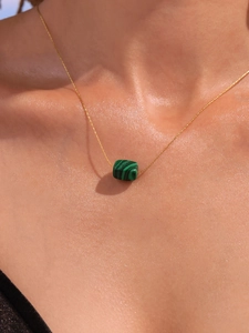 Macro detail of square green malachite pendant with 18k gold plated chain on skin
