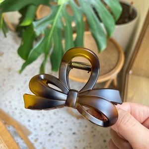 Close-up of tortoise shell bow hair claw clip with golden metal spring mechanism