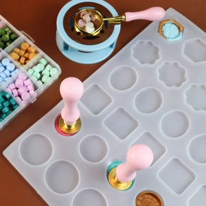 Macro shot of wax seal kit with white silicone mold, stamps, and colorful wax beads
