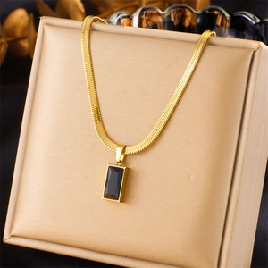 Detail of gold snake chain necklace featuring a black rectangular pendant on a display box