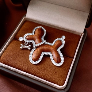 Detail of wooden balloon dog brooch with zircon stones and bone pendant on velvet