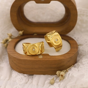 Detail of gold sun and star engraved earrings with small diamonds on vintage lace background