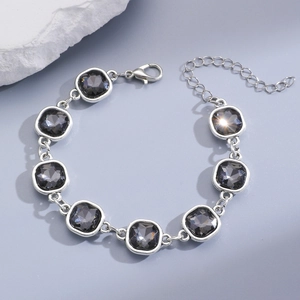 Close-up of silver chain bracelet with square grey stones and lobster clasp detail