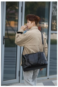 Man carrying a black PU leather weekend travel bag with adjustable shoulder strap