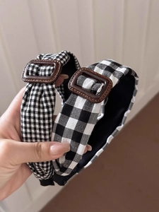 Détail d'un serre-tête vintage à carreaux noir et blanc avec boucle décorative brune