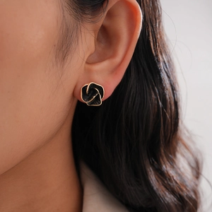 Close-up of elegant black enamel rose earring with golden edges on a model ear