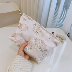 Detail der rosa Blumenstickerei und des Stofflabels auf der Kosmetiktasche aus Stoff