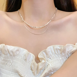 Detail of double-layer silver bow necklace with elegant zircon beads on a female model
