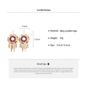 Detail view of gold alloy geometric earrings with leather tassels and 9.5cm length measurements