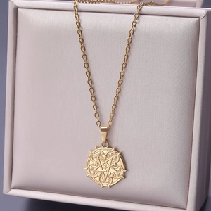 Macro view of gold stainless steel necklace featuring a star and snake round pendant
