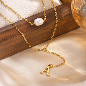 Detail of gold layered Y-necklace featuring a white pearl and an 'A' letter pendant
