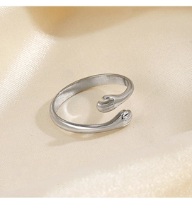 Detailed view of silver hug ring with hand design on wrinkled beige silk fabric