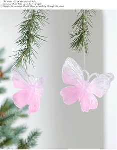Close-up of pink glitter butterfly ornaments hanging on green Christmas tree branches