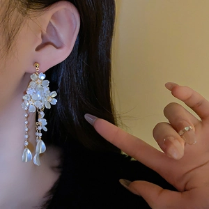 Détail de longues boucles d'oreilles fleur et perle montrant le drapé et le design