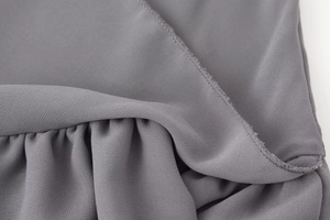 Vue macro du tissu gris en mousseline avec bords à volants et texture plissée de robe