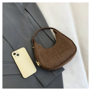 Brown textured felt hobo bag with gold hardware placed on a gray suit jacket background