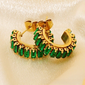 Macro detail of gold C-shaped earrings with emerald-green rectangular zirconia stones