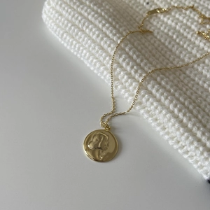 Close-up of gold 925 sterling silver coin necklace with female portrait relief detail