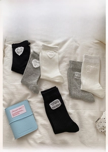 Close-up of cotton crew socks with heart-shaped lace patches in black, white and grey