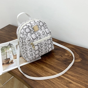 Detail of a small black and white snakeskin print backpack with a white handle on a table