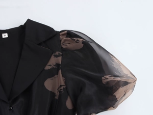 Détail des manches bouffantes en organza imprimé et du col sur une robe noire