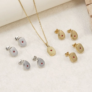 Gold and silver jewelry set featuring starburst earrings and ruby red stone necklaces