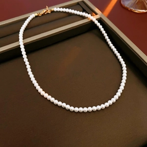 Vue détaillée d'un collier de perles blanches rondes avec fermoir doré sur plateau