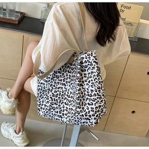 Vue détaillée du sac cabas en toile à motif léopard avec large bandoulière beige sur mannequin