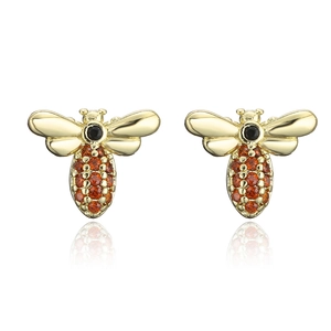 Macro shot of gold-plated bee earrings with amber and black zircon stones on white backdrop