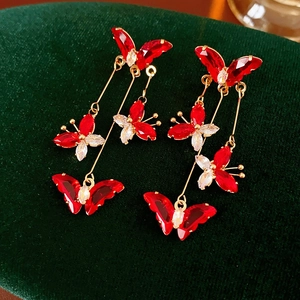 Vue macro de boucles d'oreilles dorées avec papillons en cristal rouge sur velours vert