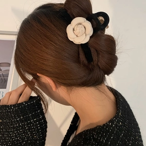 Elegant black velvet claw clip with white camellia flower in a stylish hair-updo