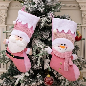 Pink Nordic Christmas stockings with plush Santa and Snowman hanging on a tree