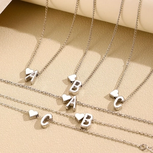 Colliers argentés avec pendentifs cœur et lettres A, B, C présentés en ensemble stylé